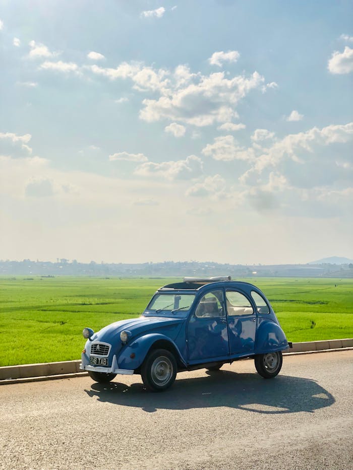 Offerings A classic vintage Citroen driving along a rural road on a sunny day in Antananarivo.