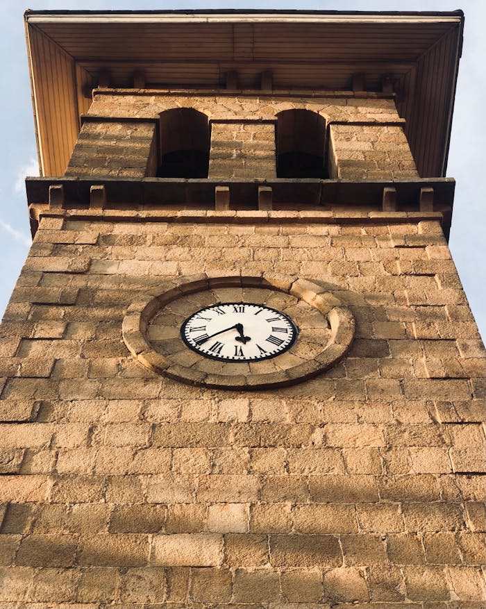 Home Low angle view of a historic clock tower facade in Antananarivo, Madagascar, captured in warm daylight.